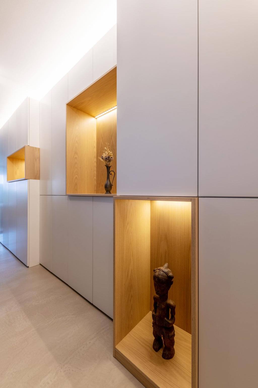 Placards dans un long couloir avec niches éclairées