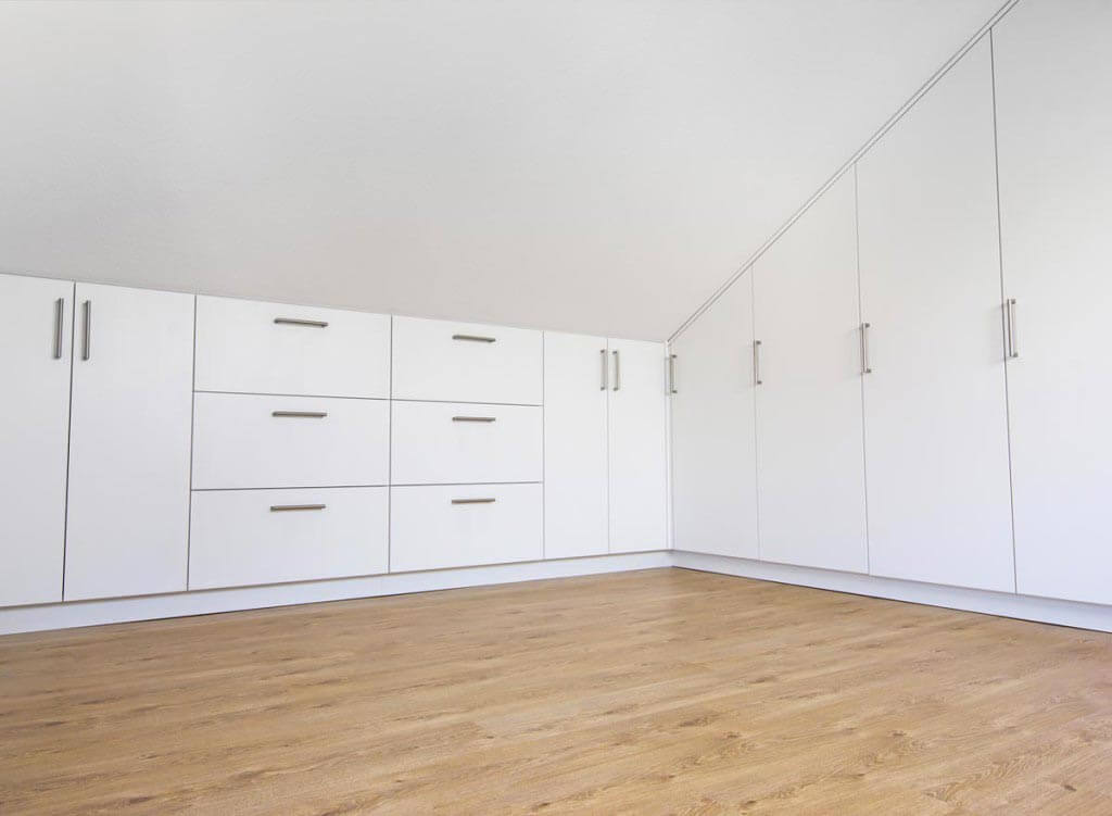 Aménagement de combles avec placards blancs à poignées
